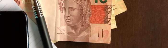 Brazilian money in paper, note paper and cellphone - top view